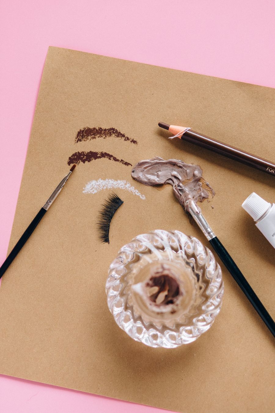 Flat lay of makeup products on a pink background